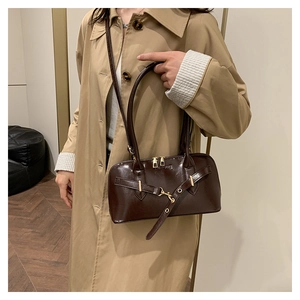 Dark brown patent leather shoulder bag with gold hardware and logo on model side view