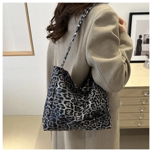 Detail of a large leopard print tote bag styled with a beige blazer in a minimalist room