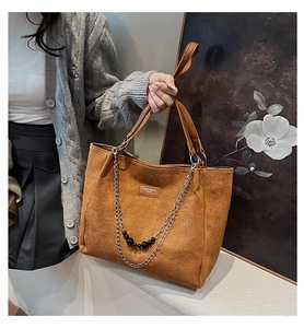 Dettaglio della borsa tote in pelle scamosciata marrone con catena e perla nera