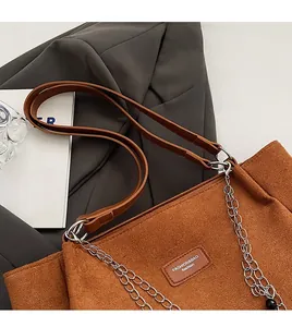 Dettaglio di una borsa tote in pelle scamosciata marrone con tracolla in pelle e metallo