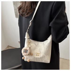 Detail of off-white pleated shoulder bag featuring a cute plush alpaca charm and logo patch