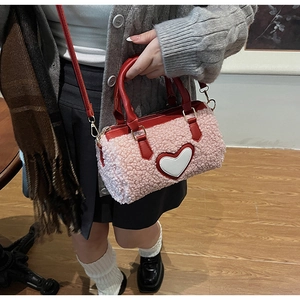 Detail of pink faux fur barrel bag featuring red leather handles and heart patch