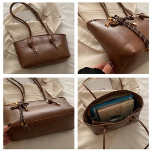Dettaglio di borsa tote grande in pelle marrone con spalline annodate e pendente