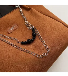 Dettaglio della borsa tote in pelle scamosciata caramello con catena d'argento
