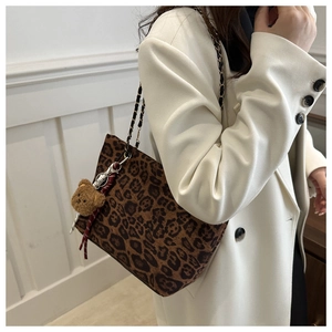 Leopard print tote bag with gold chain strap and plush bear charm on white blazer