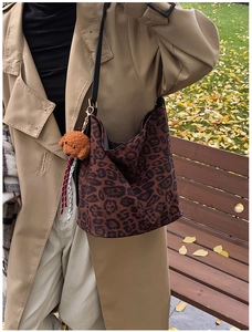 Detailed view of leopard print tote bag with black strap and plush puppy charm decor