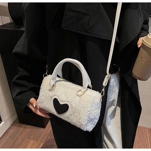 Détail du mini sac Boston en peluche blanche avec patch cœur noir et finitions dorées