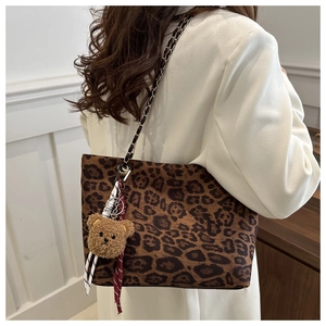 Detailed view of leopard print tote bag with gold chain strap and plush bear charm