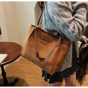 Dettaglio borsa tote in pelle scamosciata marrone con catene e perline nere