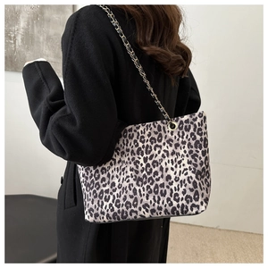 Close-up of leopard print tote bag with a black leather and gold chain shoulder strap