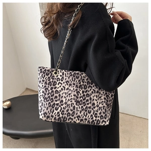 Detail of leopard print tote bag with golden chain strap worn by model in casual setting
