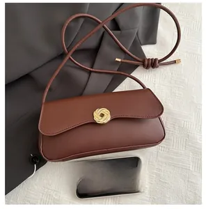 Brown leather baguette bag featuring a gold woven clasp with a smartphone for scale