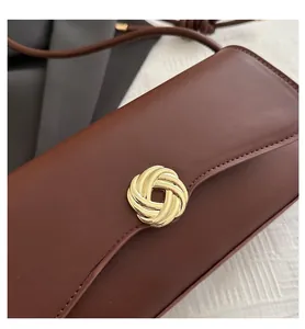Detail shot of vintage dark brown leather bag featuring a gold spiral knot metal clasp