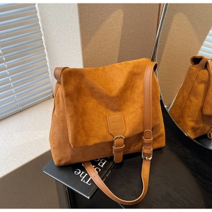 Detail of caramel suede messenger bag featuring retro buckle and premium matte texture