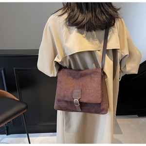 Detailed view of dark brown suede messenger bag worn with a khaki autumn trench coat