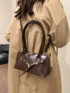 Vintage dark brown glossy bowling bag with gold buckle and fashion text on a female model