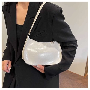 Detail of a creamy white retro underarm bag showing glossy leather texture and gold zipper