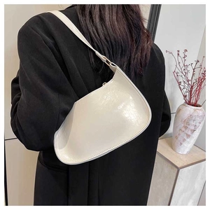 White semi-circle shoulder bag in glossy patent leather finish shown on a model