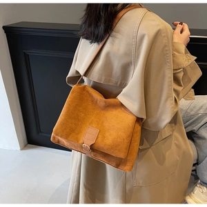 Detail view of a vintage caramel suede crossbody bag worn with a khaki autumn trench coat