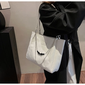 Dettaglio della borsa tote bianca con pelle testurizzata e catena in metallo e perle