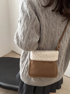 Petit sac seau en daim marron et peau de mouton blanche porté par un mannequin