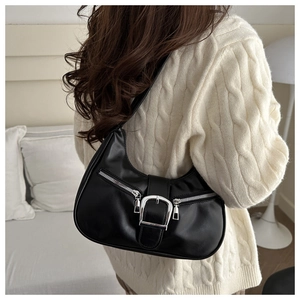 Détail d'un sac demi-lune en cuir noir avec boucle argentée sur un pull en maille