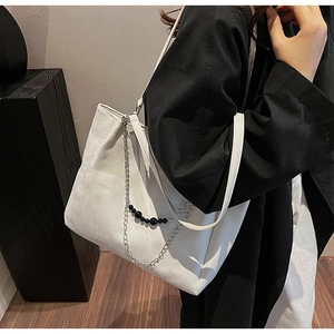Dettaglio della borsa tote bianca con catena argento, perline nere e trama martellata