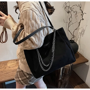 Dettaglio della borsa tote nera con catena d'argento indossata con maglieria autunnale