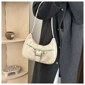 Detail der beigefarbenen Hobo-Tasche mit silberner Schnalle und Reißverschlüssen aus Leder