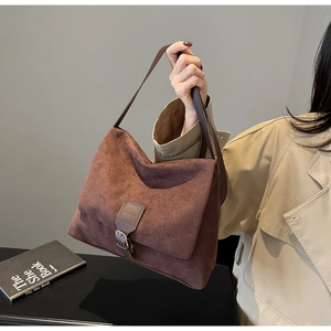 Detail view of dark brown suede shoulder bag with vintage metal buckle and leather strap