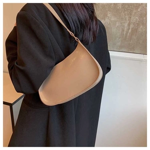 Side view of a khaki minimalist leather underarm bag worn with a black blazer