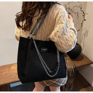 Dettaglio di una grande borsa tote nera opaca con doppie catene e perline decorative