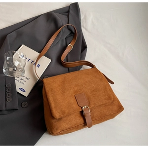 Detailed view of brown suede messenger bag with adjustable strap and buckle on blazer