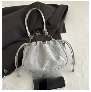 Detail of silver ruched cloud bag with drawstring closure and delicate chain strap