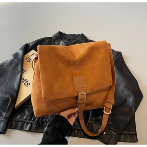 Detail of caramel suede messenger bag with vintage buckle and adjustable strap