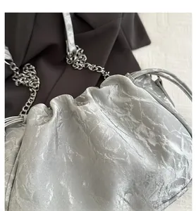 Macro view of silver pleated cloud bag with metallic texture and thin chain strap
