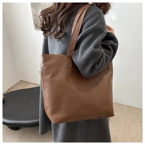 Bolso tote marrón de piel sintética vintage usado al hombro con un abrigo largo