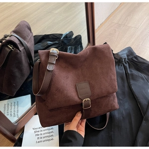 Detailed shot of dark brown suede messenger bag with retro metal buckle and matte texture