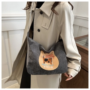 Detail of grey corduroy shoulder bag featuring a cute cat patch and embroidery accents