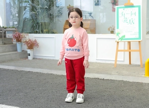 Detail of pink tomato print sweatshirt and red trousers kids autumn outfit set