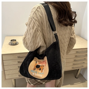 Detail of black corduroy shoulder bag with cute cartoon cat embroidery and wide strap
