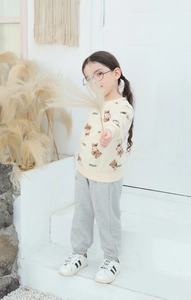 Detail of cream sweatshirt with bear print and grey joggers on a white staircase