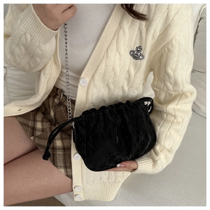 Detail of black pleated bucket bag with drawstring closure and silver chain strap