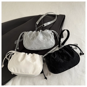 Detailed view of ruched crossbody bags in silver, white, and black with satin texture