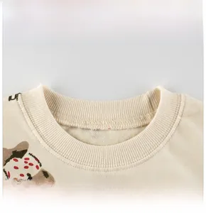 Detail view of cotton rib neckline and brown cartoon print on cream baby sweatshirt