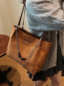 Borsa tote in camoscio marrone con manici in pelle e catena indossata da una modella