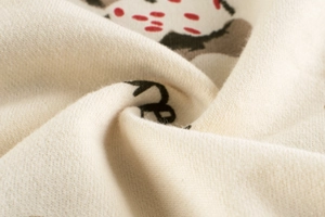 Close-up of soft knitted cotton fabric featuring red polka dots and floral patterns