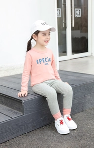 Outdoor view of girl's pink long sleeve t-shirt with SPECIAL GIRL text and gray pants
