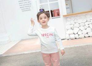 Detail shot of a girl wearing a white long-sleeve cotton T-shirt with pink logo and pants