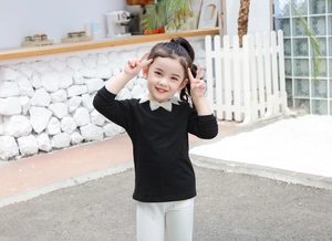 Dettaglio della t-shirt nera a maniche lunghe da bambina con fiocco bianco in cotone Lycra